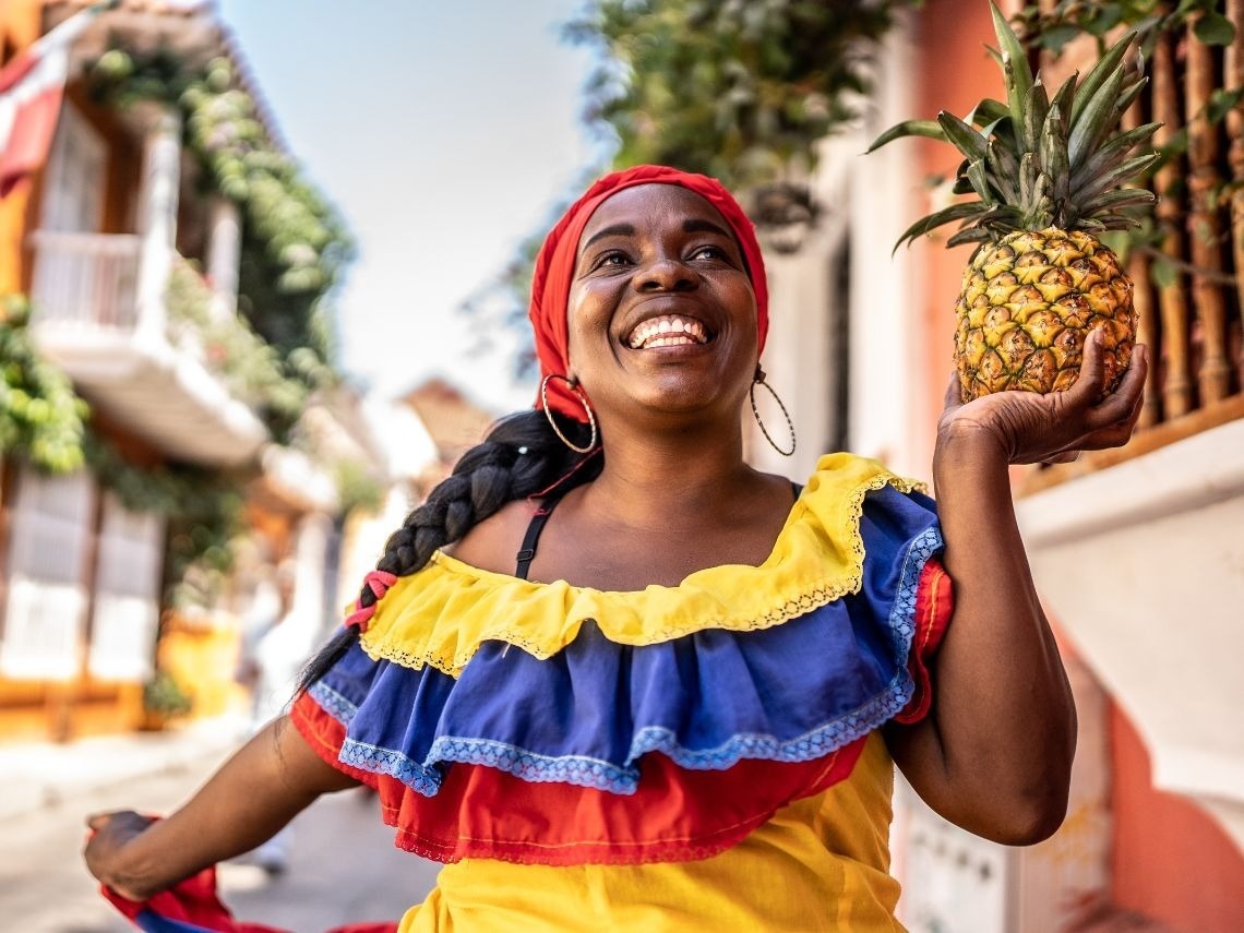 Tequendama: Corporativa, mujer sonriente con traje típico y piña.