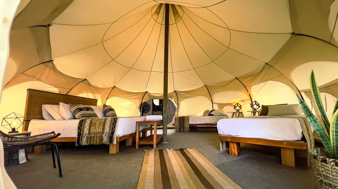 Cabañas Tequendama: acogedor interior de glamping con camas y alfombra.