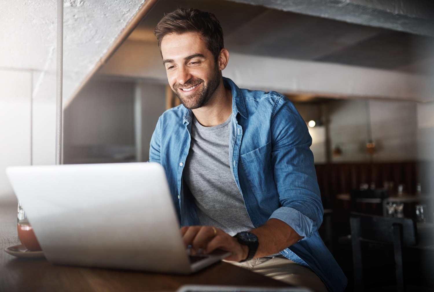 Hombre sonriente trabaja en laptop en hotel Tequendama: Corporativa