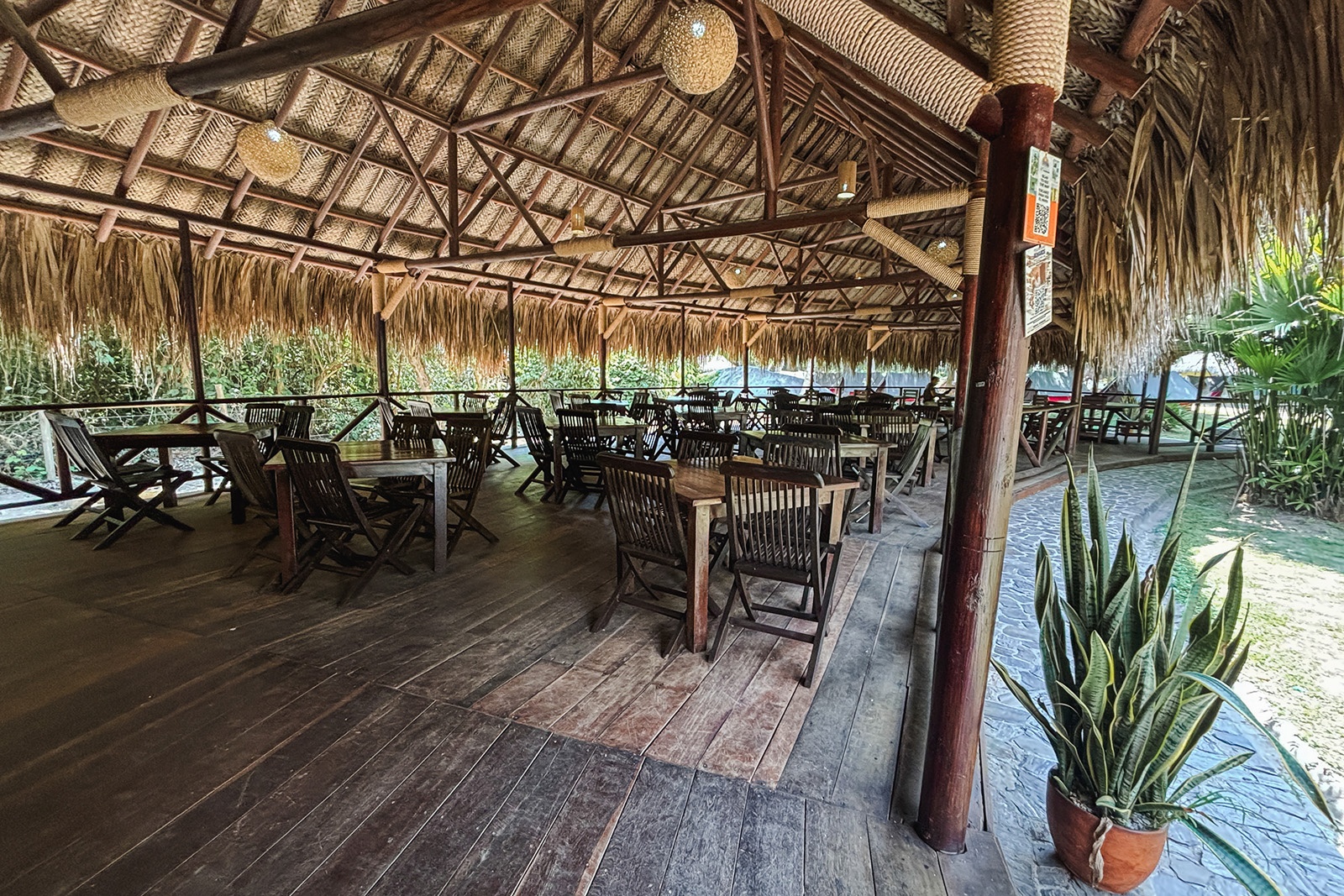 Área de restaurante al aire libre en Tequendama: Corporativa, con mesas de madera y techo de paja.
