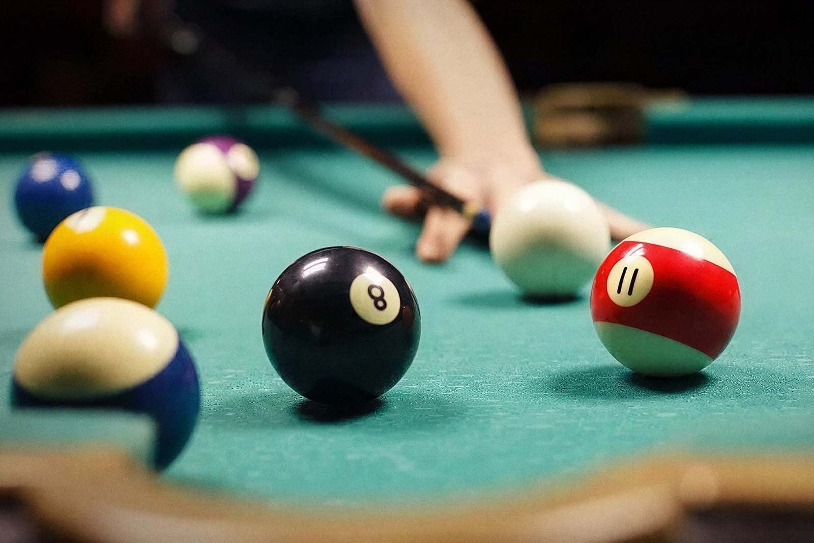 Tequendama: Corporativa - Billiard table with balls, cue stick, and player's hand.