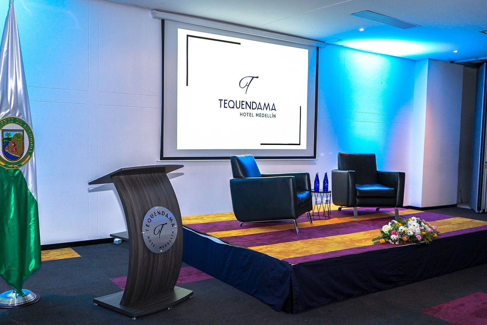 Tequendama Hotel Medellín: Stage with podium, chairs, and logo. Perfect for events.
