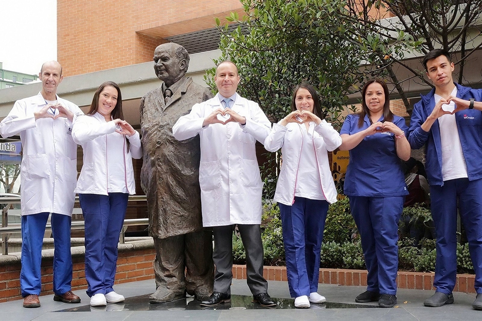 Tequendama: Corporativa, médicos forman corazón con las manos junto a estatua.