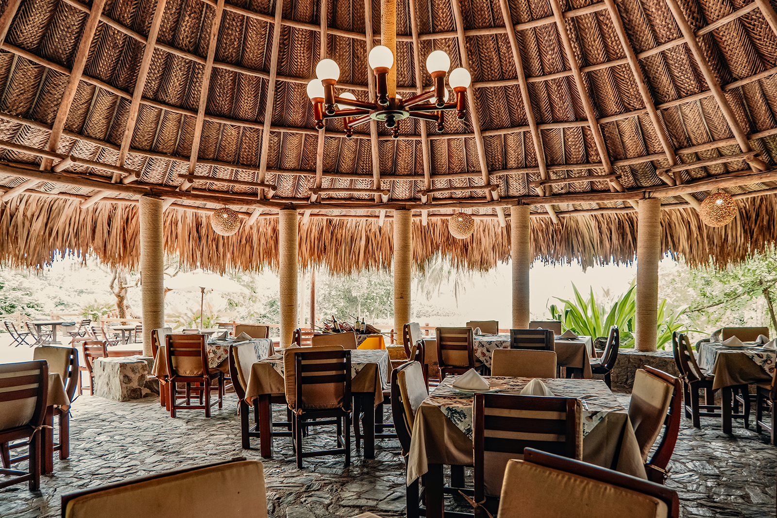 Restaurante al aire libre Tequendama Corporativa con mesas cubiertas y techo de paja.