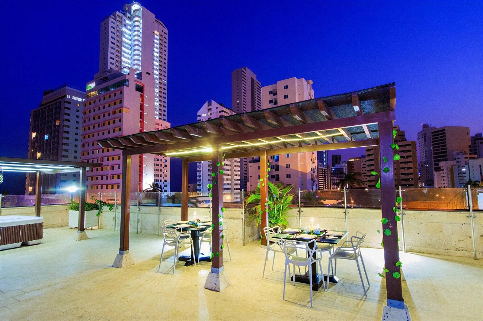 Terraza Tequendama: Mesas, jacuzzi y vistas corporativas nocturnas.