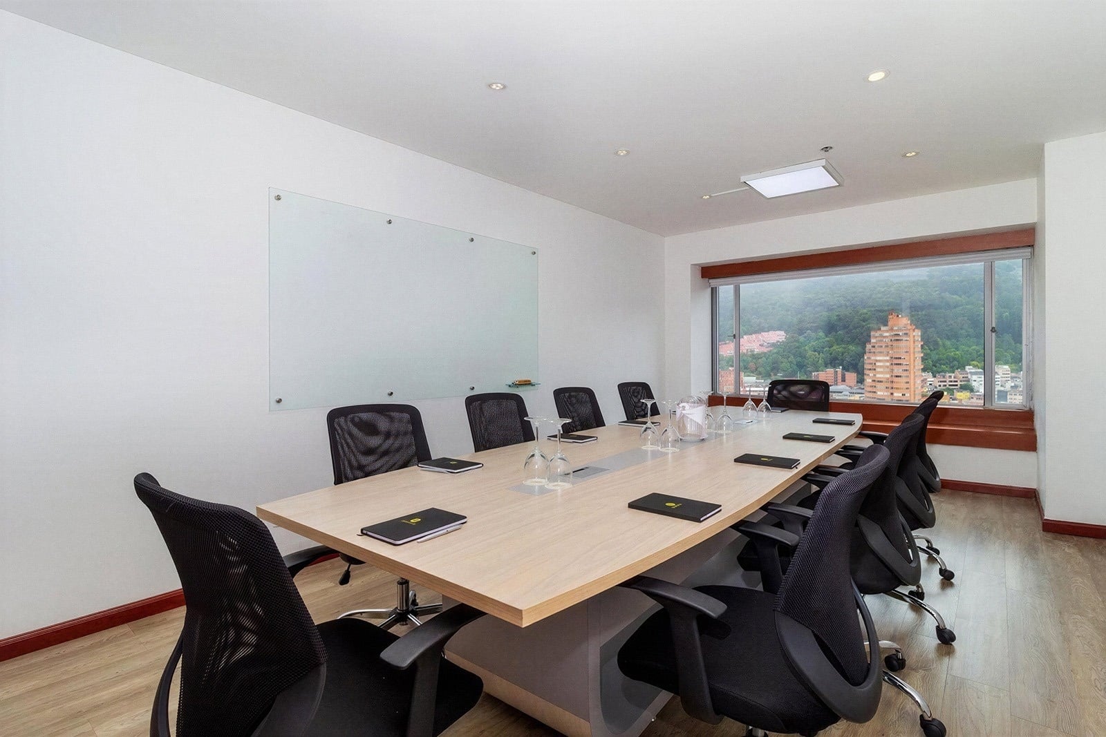 Modern meeting room with large table, chairs, and whiteboard for events. Ideal for Tequendama Suites Bogotá events.