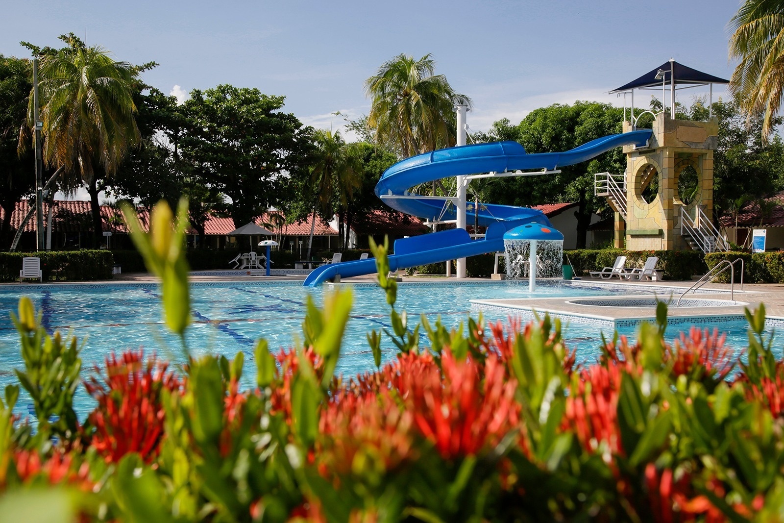 Hotel Los Puentes Comfacundi: Resort pool with blue waterslide & lush greenery.
