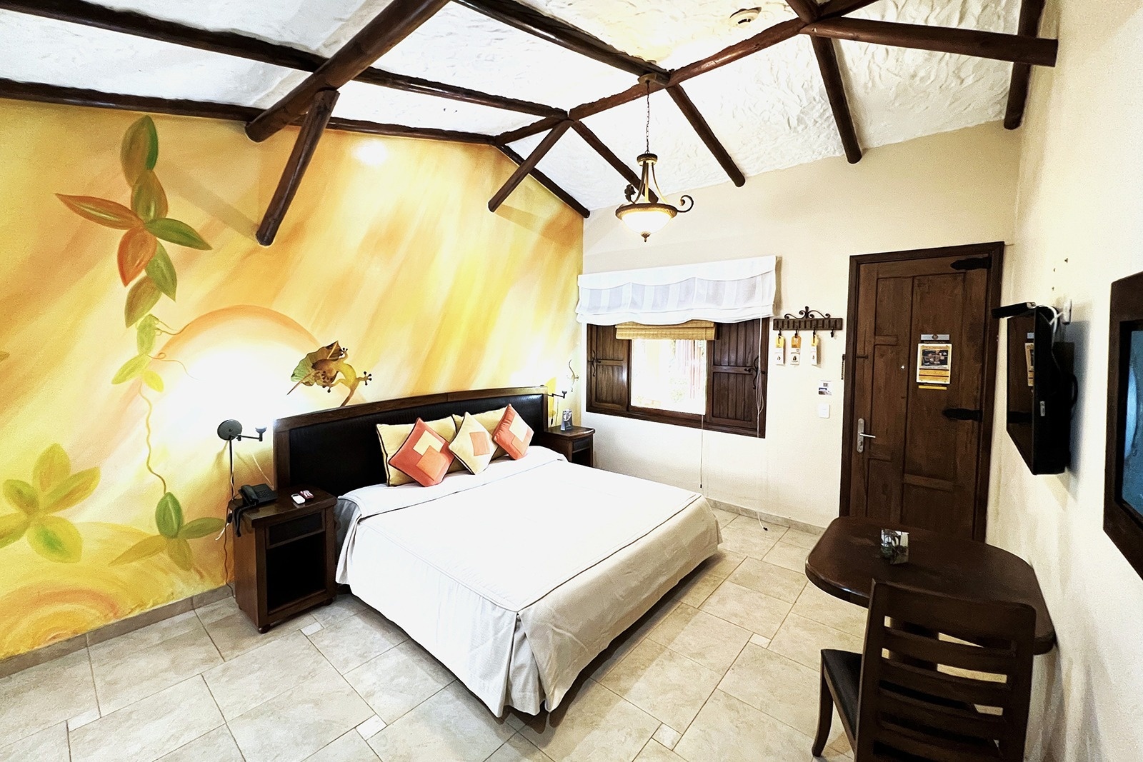 Tequendama Hotel Campestre Villavicencio: King bed with tropical mural, TV, and table.
