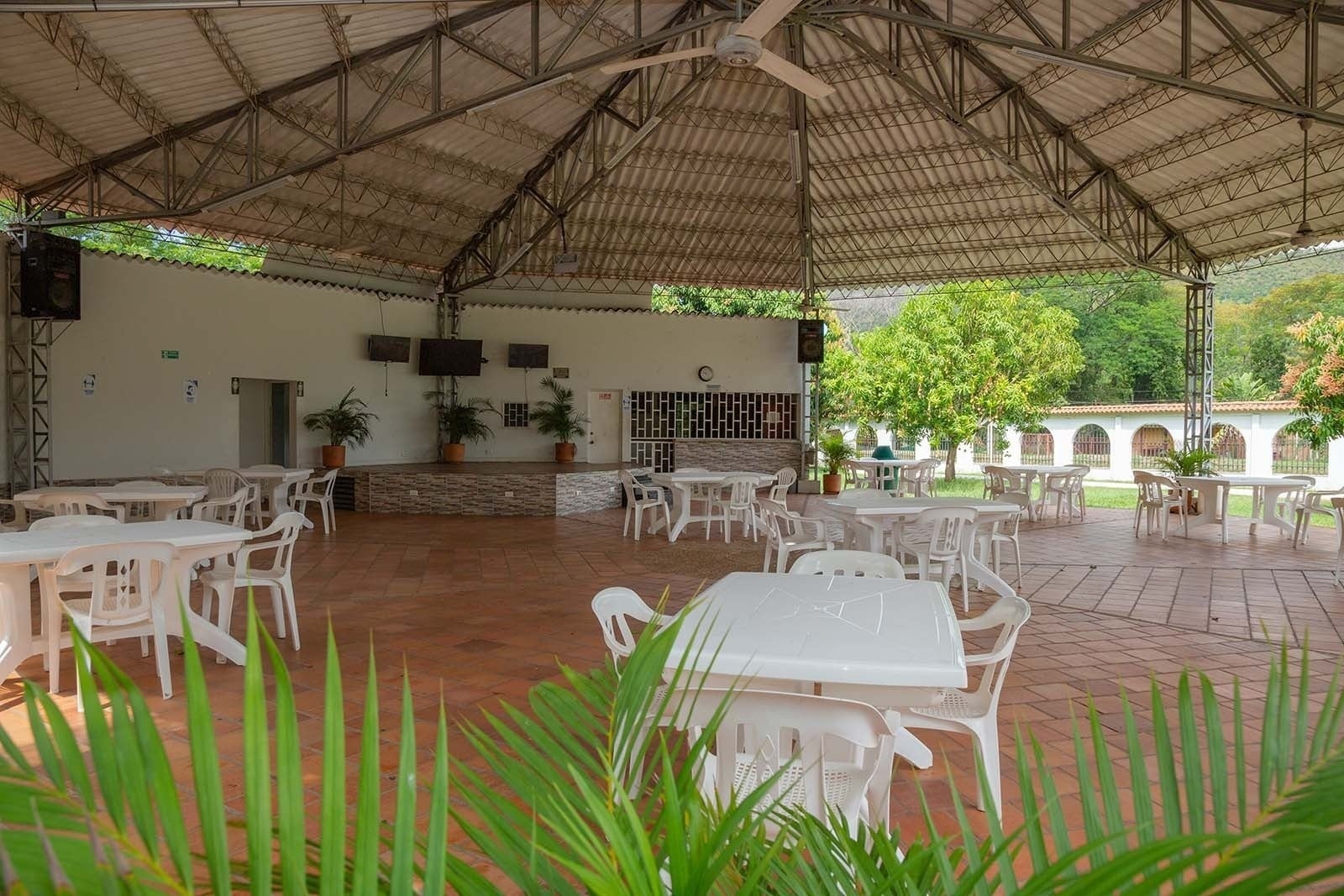 Hotel Mirador de Sumapaz: Salón cubierto con mesas y sillas blancas, ideal para eventos y descanso al aire libre.