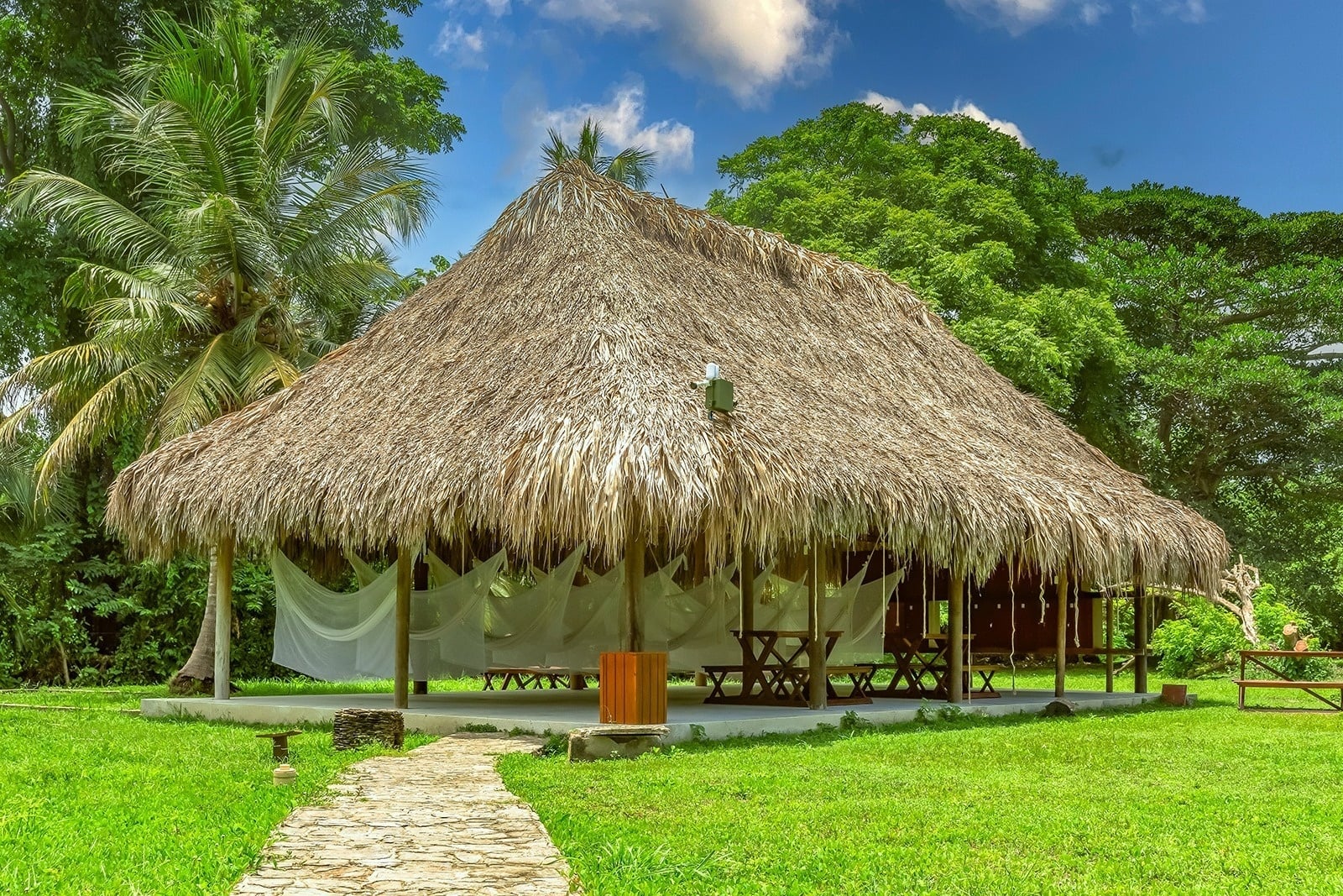 Ecohabs Tequendama: Thatched roof bungalow with white netting, surrounded by lush greenery near Tayrona Park.