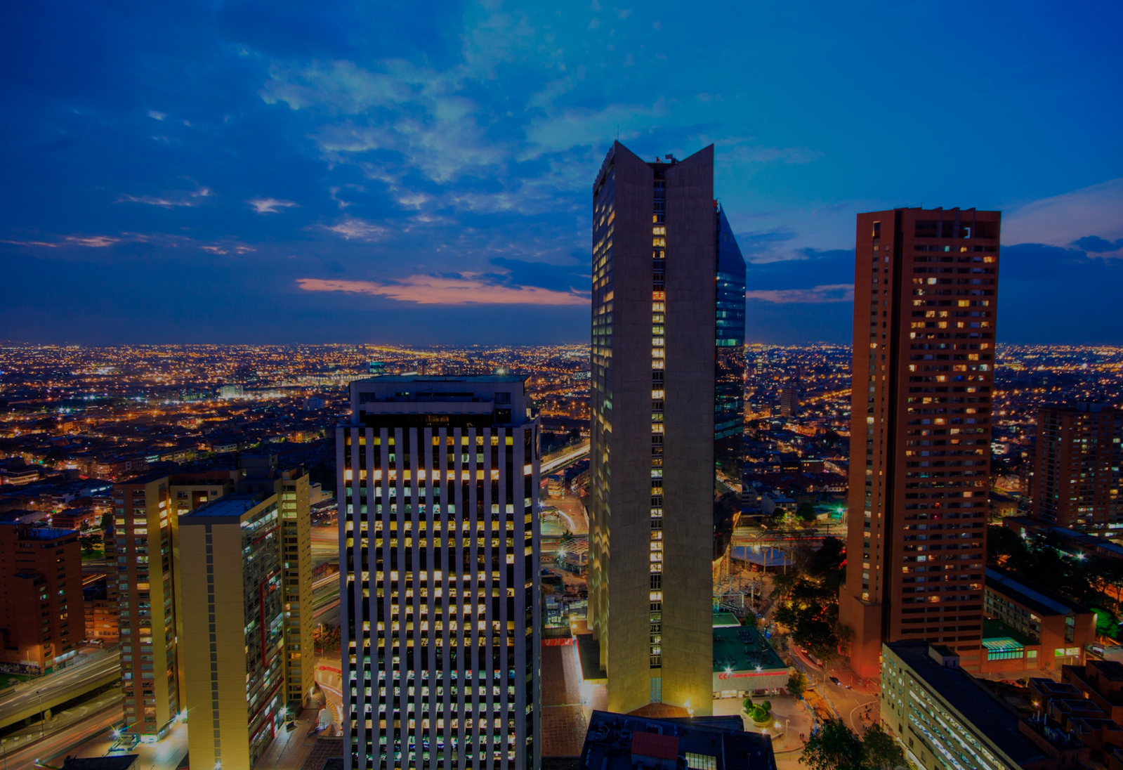 Tequendama: Corporativa vista nocturna de edificios y ciudad iluminada.