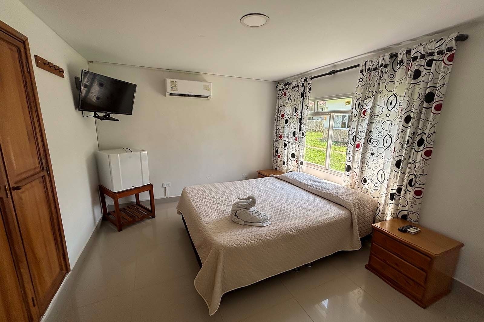 Habitación acogedora en Hotel Mirador de Sumapaz con TV, mini-nevera y ventana con vistas a la naturaleza.