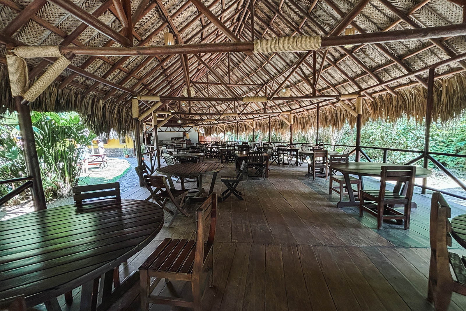 Salón tipo cabaña en Tequendama: Corporativa, mesas de madera bajo techo de palma.