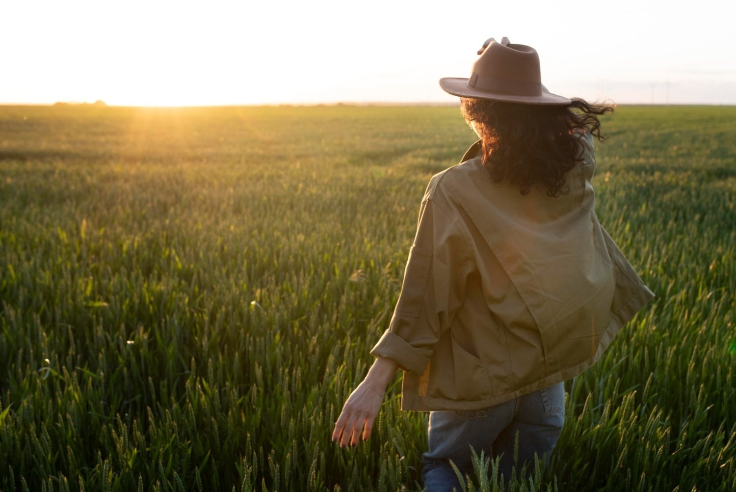 Mujer con sombrero en campo de trigo al atardecer, ideal para descanso Tequendama Corporativo.