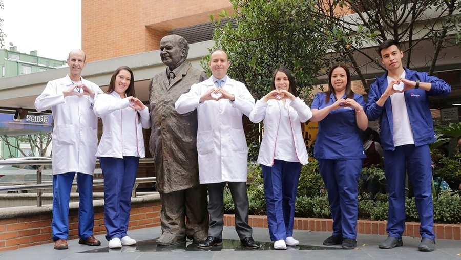 Tequendama: Corporativa - Staff forming hand hearts in front of statue and building.