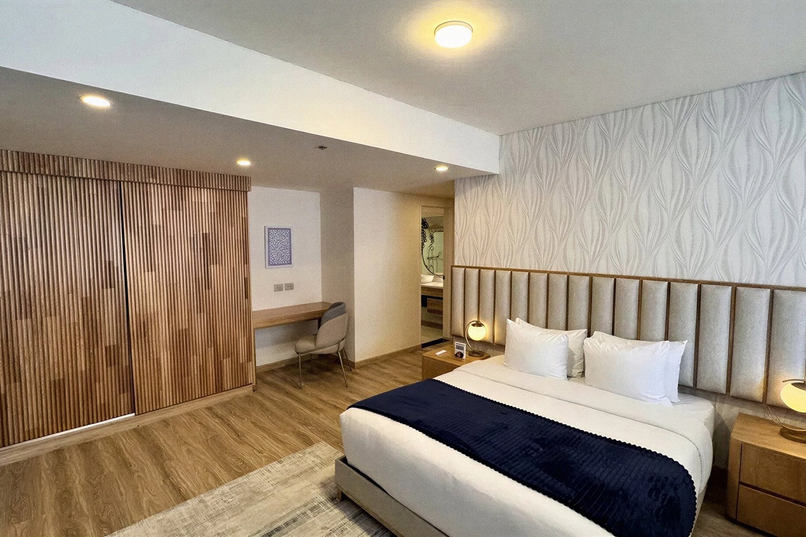 Tequendama Suites Bogotá: Modern bedroom with desk, large wardrobe, and king bed.