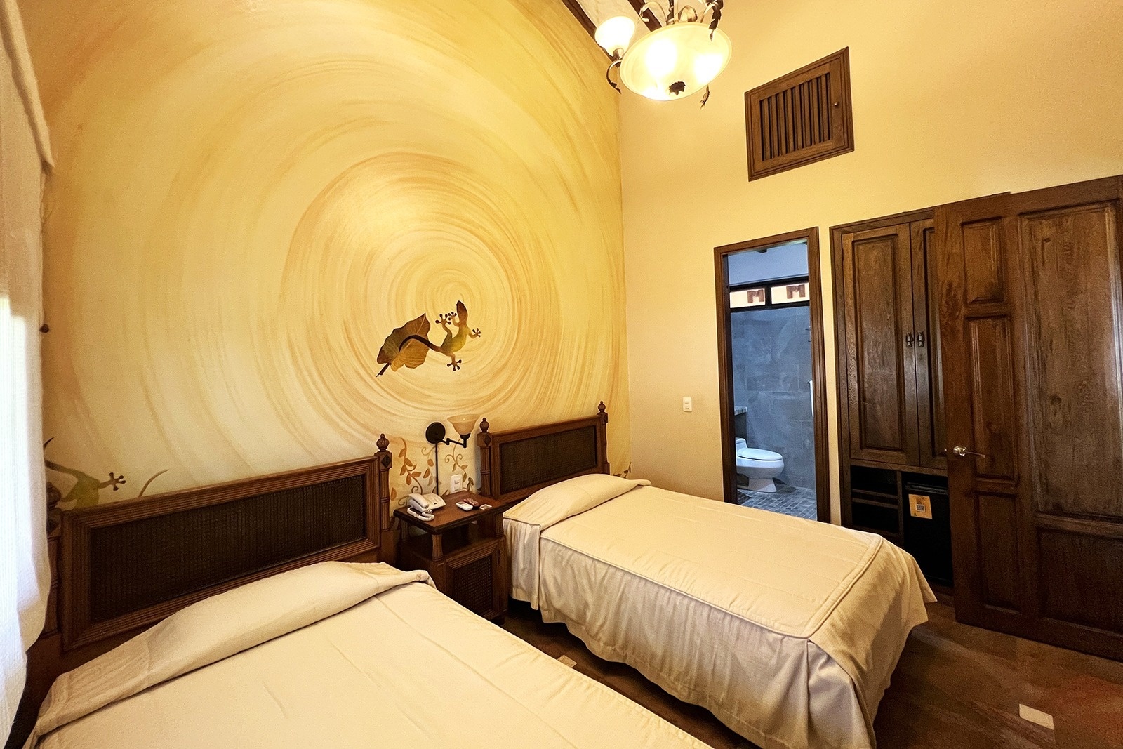 Twin beds in a room with gecko art at Tequendama Hotel Campestre Villavicencio | Nature & Relaxation
