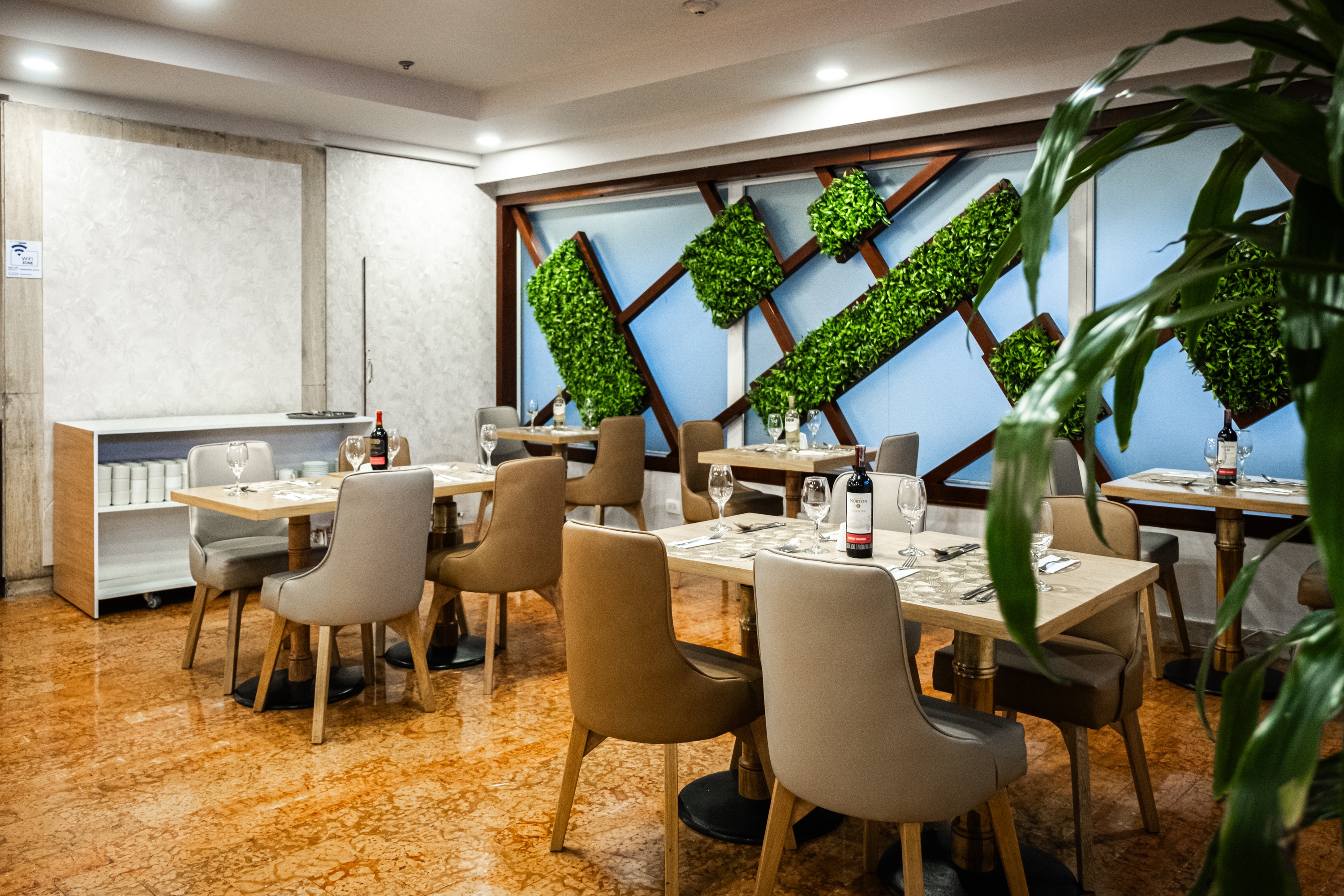 Tequendama: Corporativa - mesas listas para cenar en un elegante comedor con plantas colgantes.