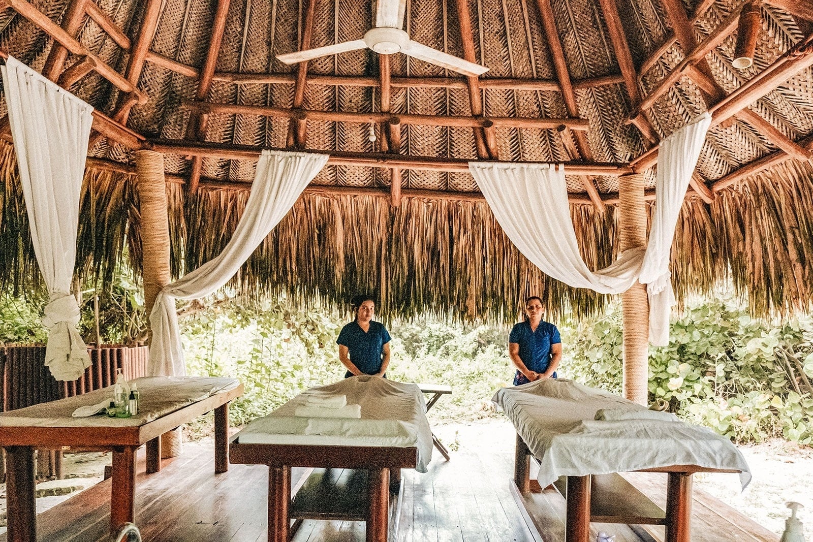 Dos masajistas en spa Tequendama: Corporativa ofrecen masajes relajantes en cabaña tropical.