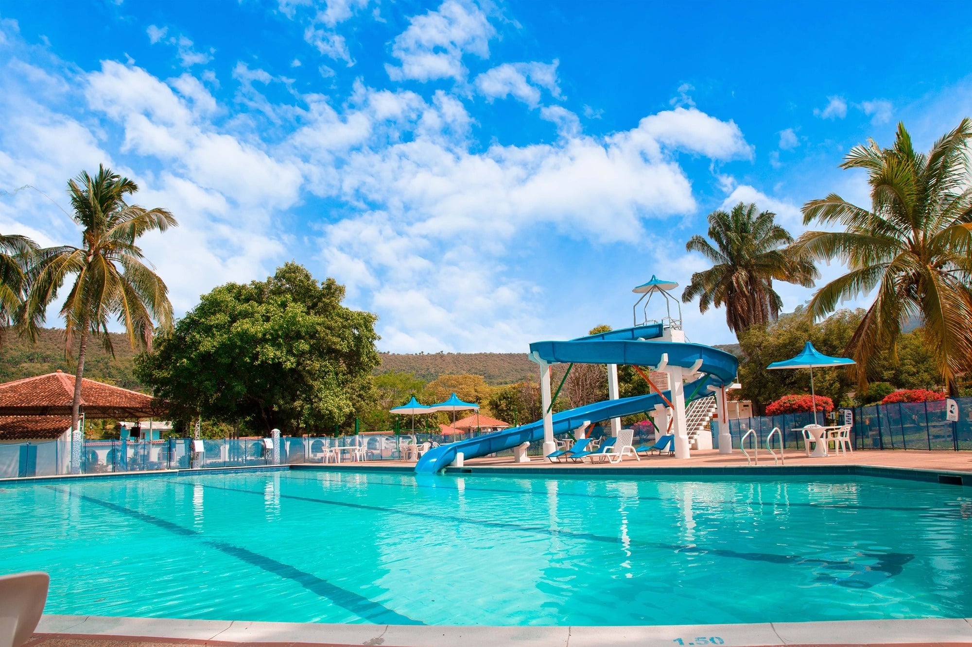 Hotel Mirador de Sumapaz: Pool with slides, palm trees, and clear blue skies.