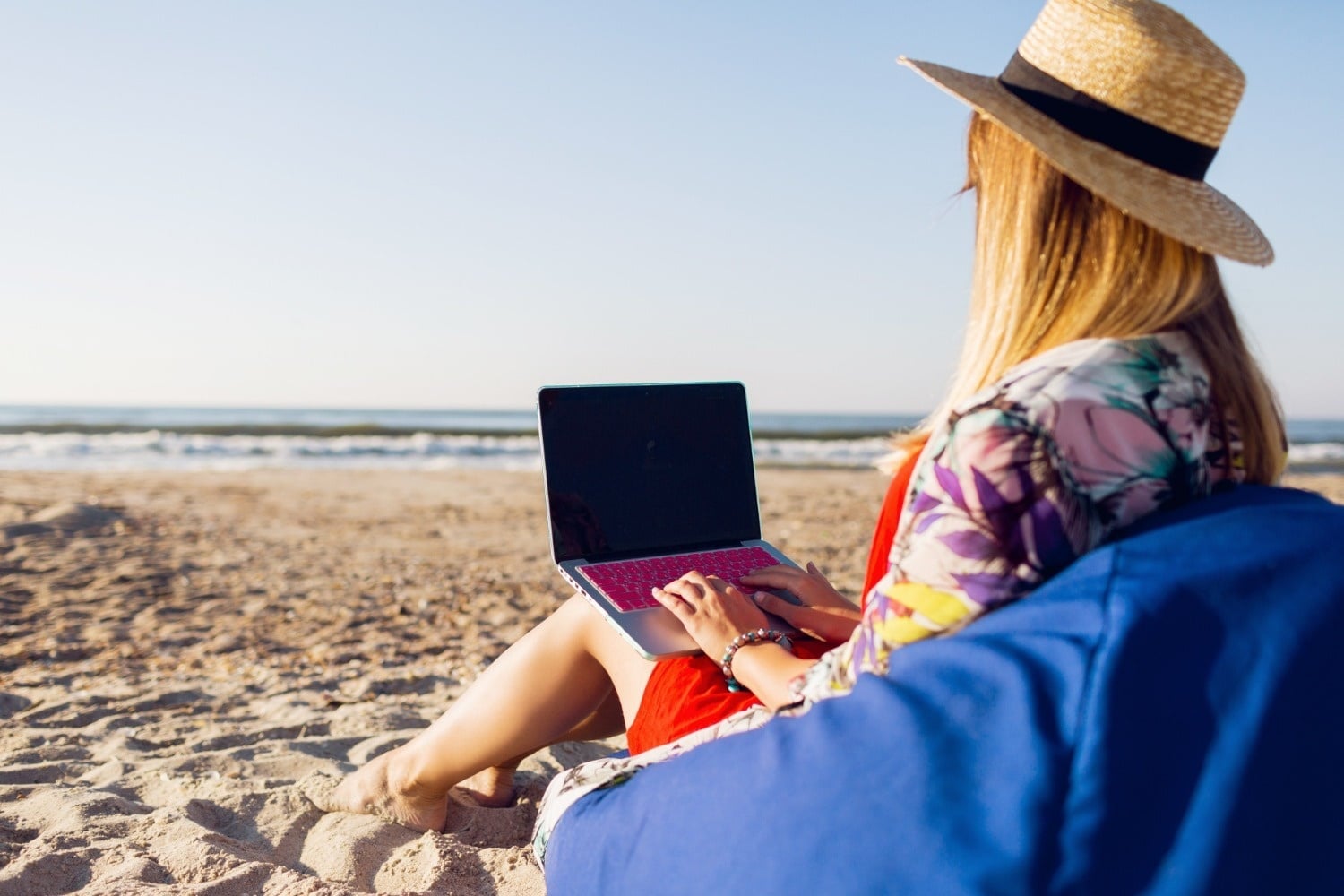 Tequendama: Corporativa - Mujer trabajando en laptop en playa con vista al mar.