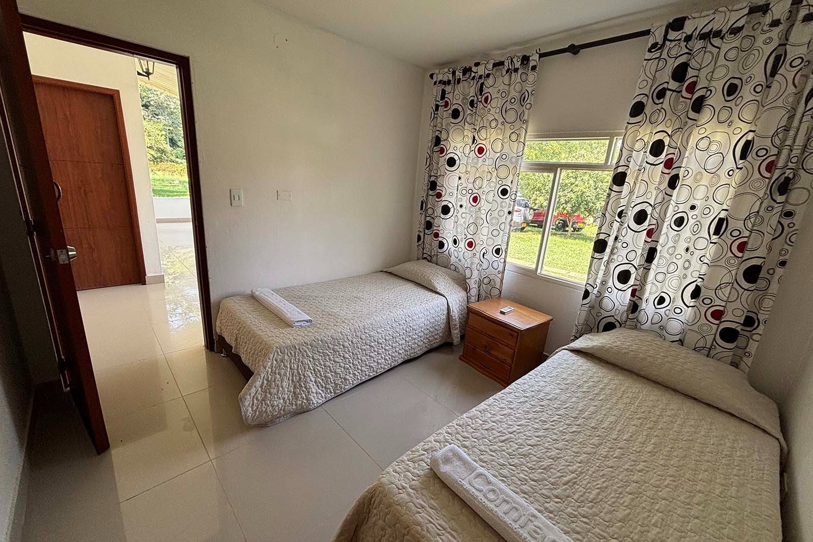 Habitación doble en Hotel Mirador de Sumapaz, con camas sencillas y vista al exterior.