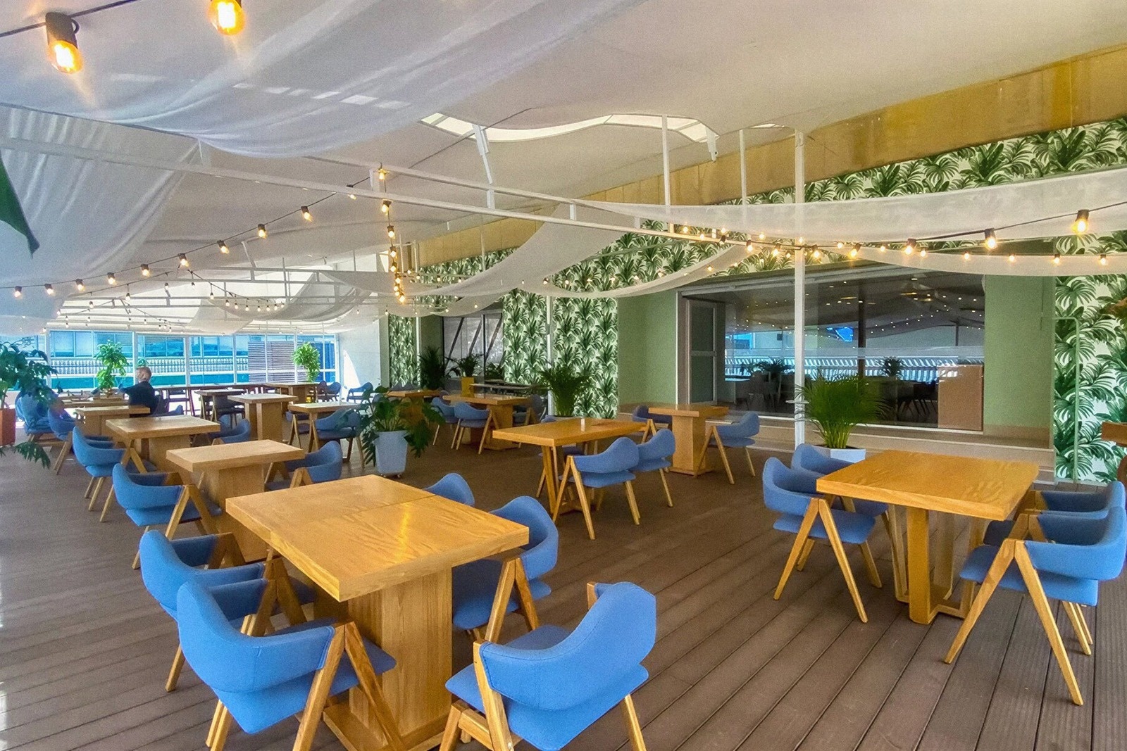 Spacious outdoor dining at Tequendama Suites Bogotá, featuring blue chairs and wooden tables.