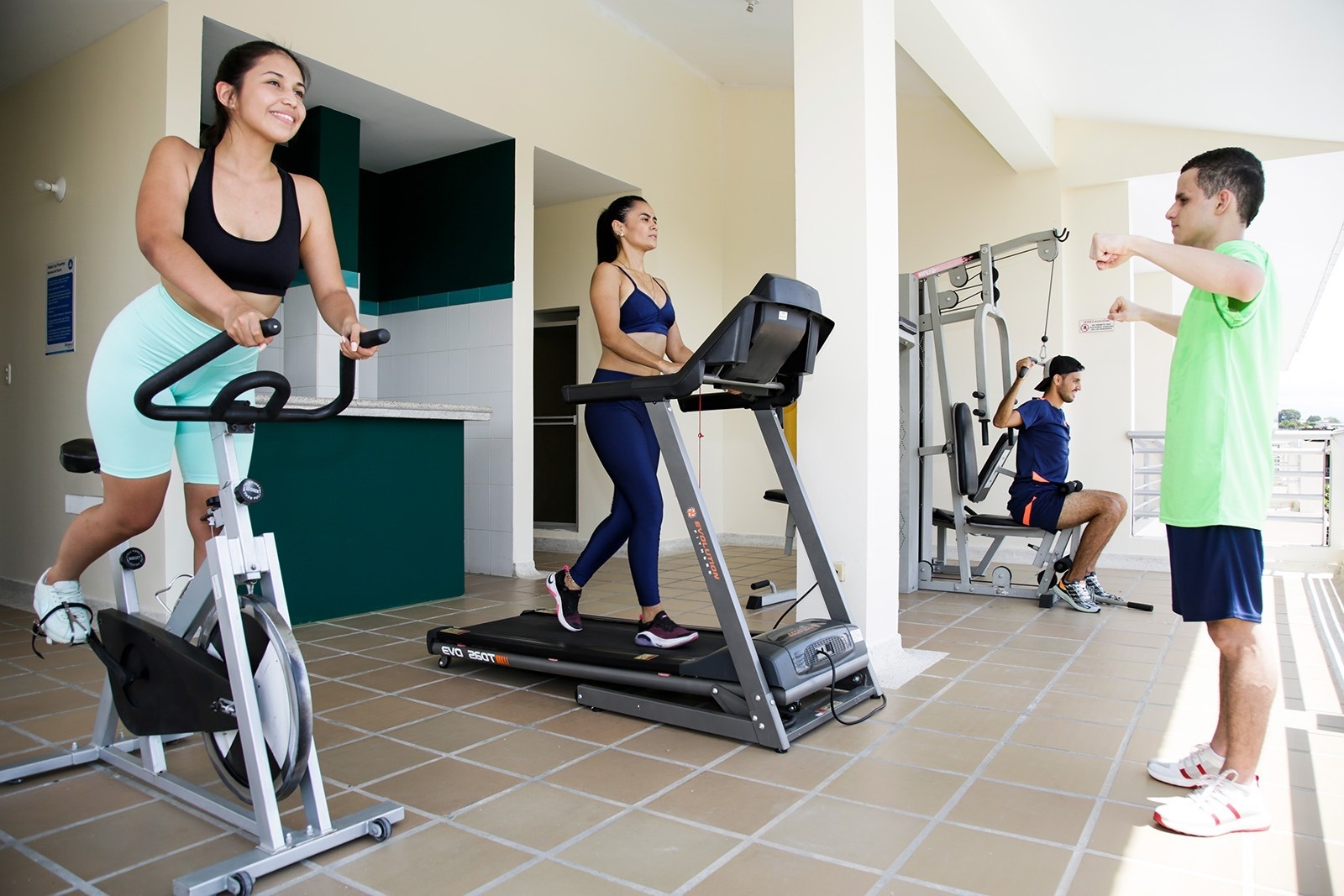 Gimnasio Tequendama: Corporativa. Personas entrenando en bicicletas estáticas, cintas de correr y máquinas.