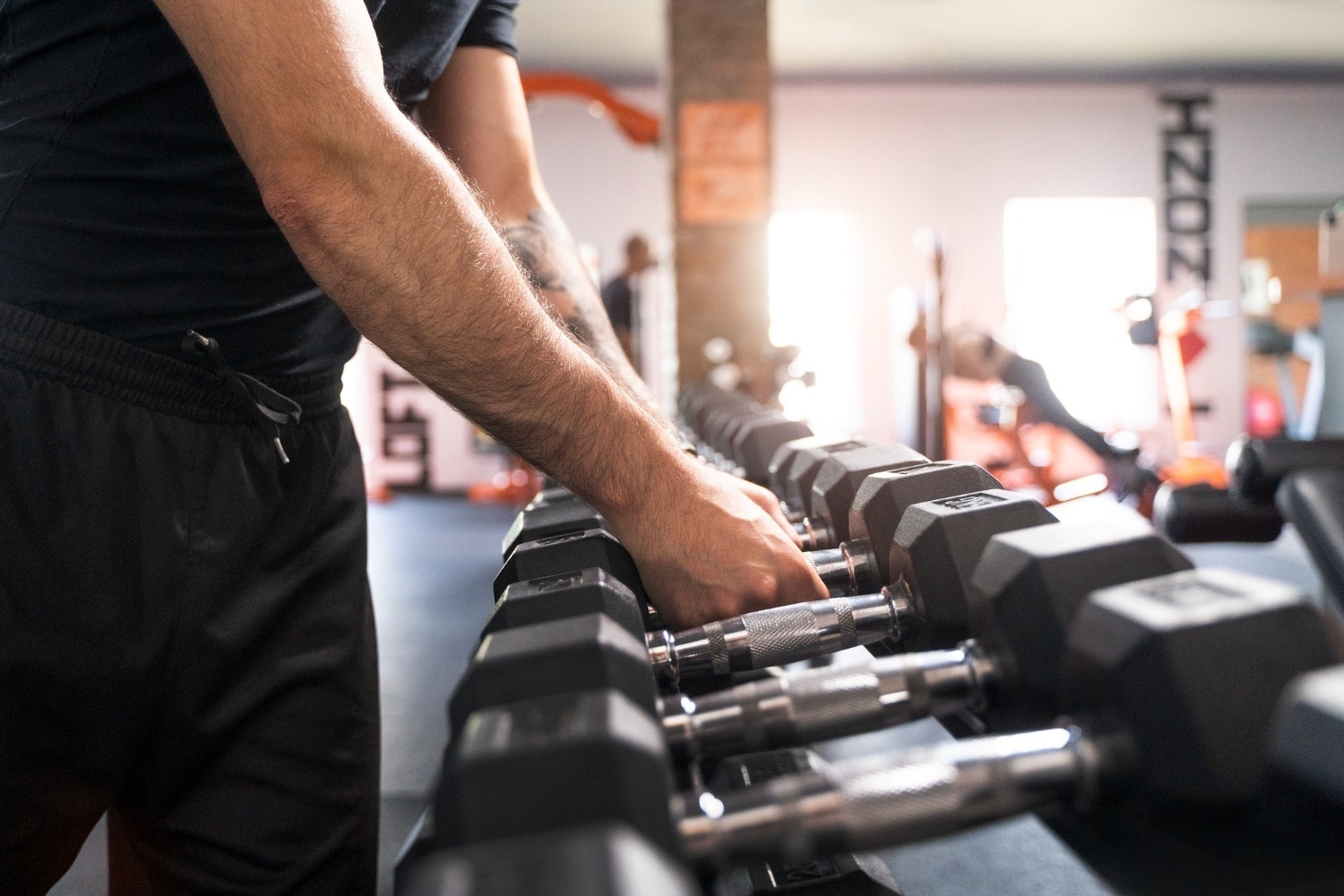 Man selecting dumbbells in Tequendama Corporativo gym.