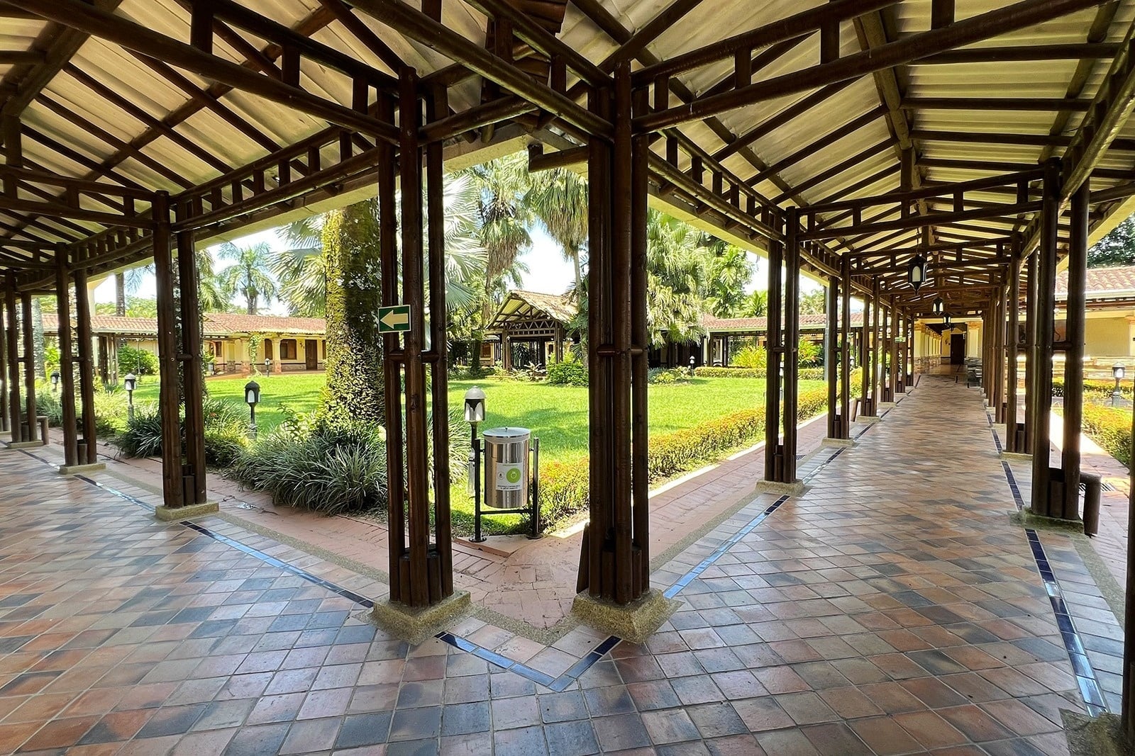 Covered walkway at Tequendama Hotel Campestre Villavicencio, surrounded by lush greenery and tropical trees.