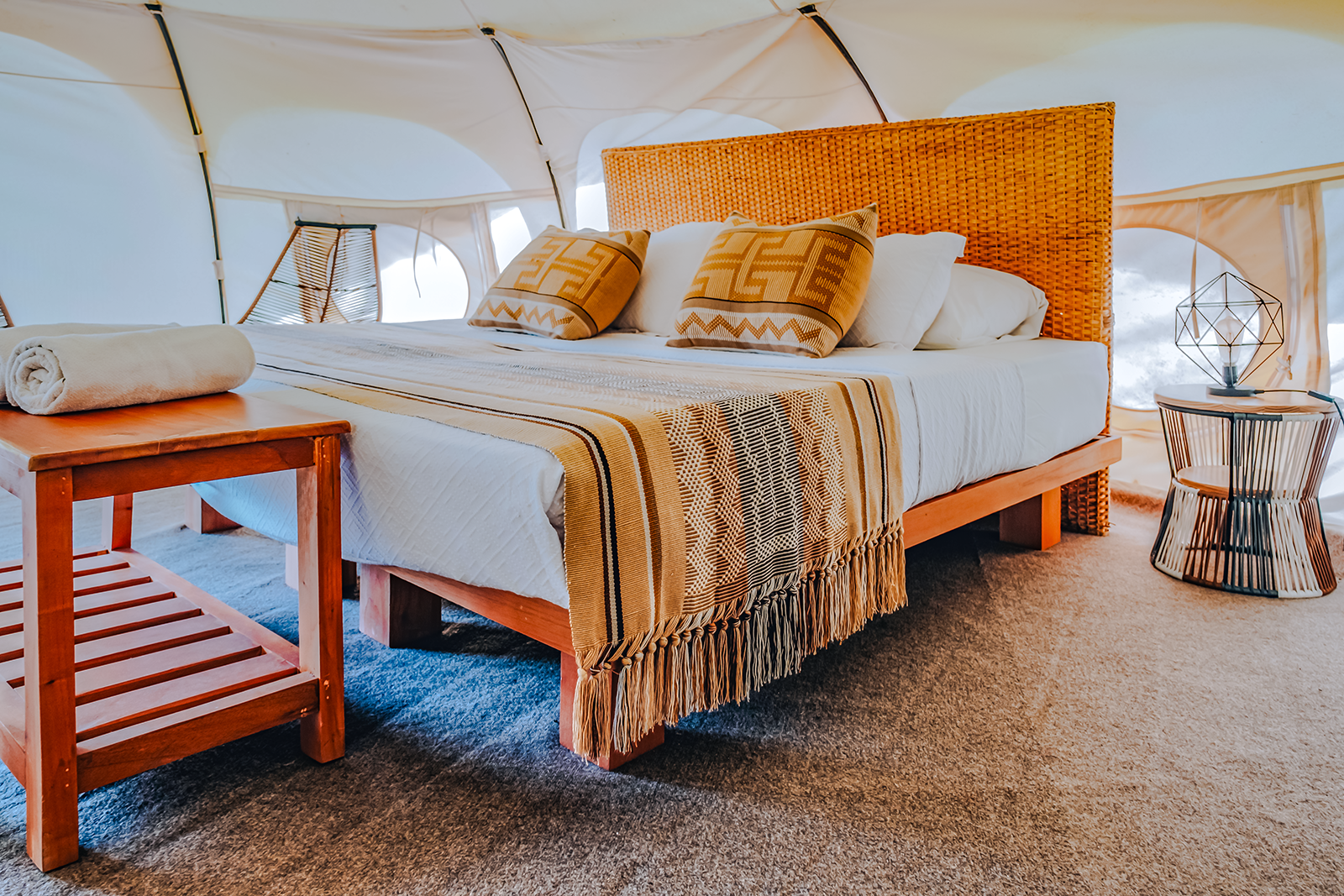 Cozy glamping tent interior with a bed and woven accents at Ecohabs Tequendama.