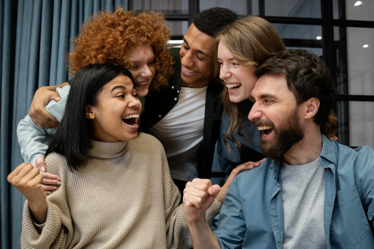 Un grupo diverso de amigos celebra riendo y abrazándose, un ambiente perfecto para tu próxima estancia Tequendama: Corporativa.