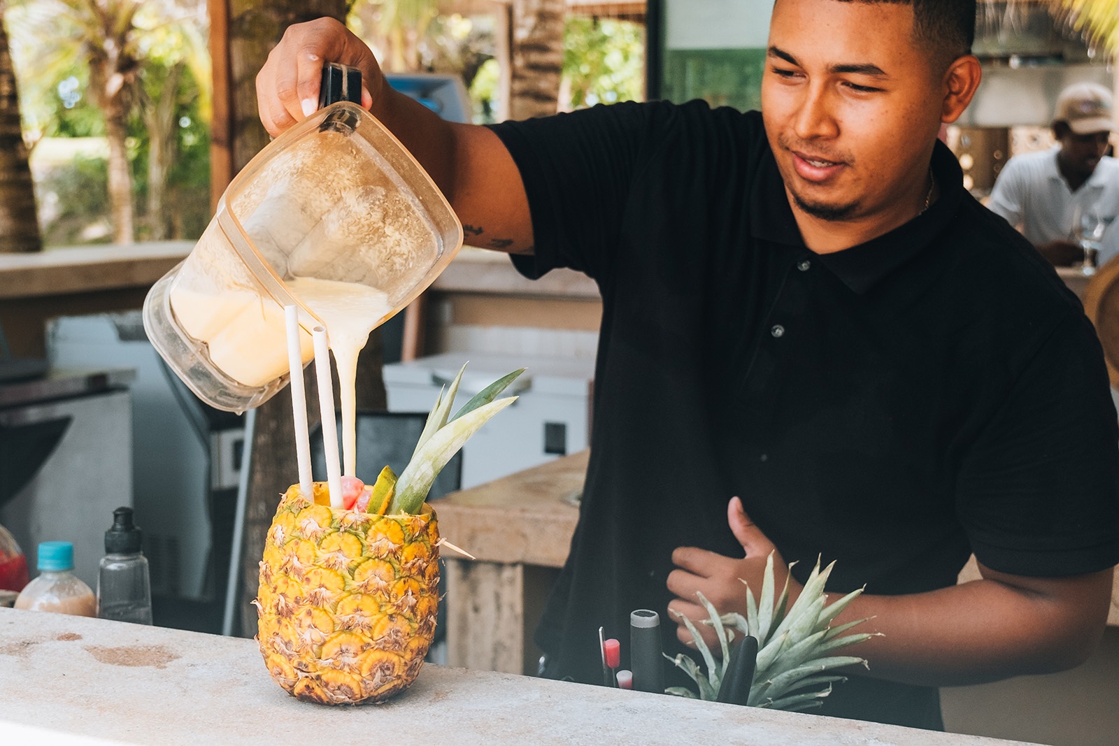 Bartender at Tequendama: Corporativa resort pours a tropical cocktail into a pineapple.