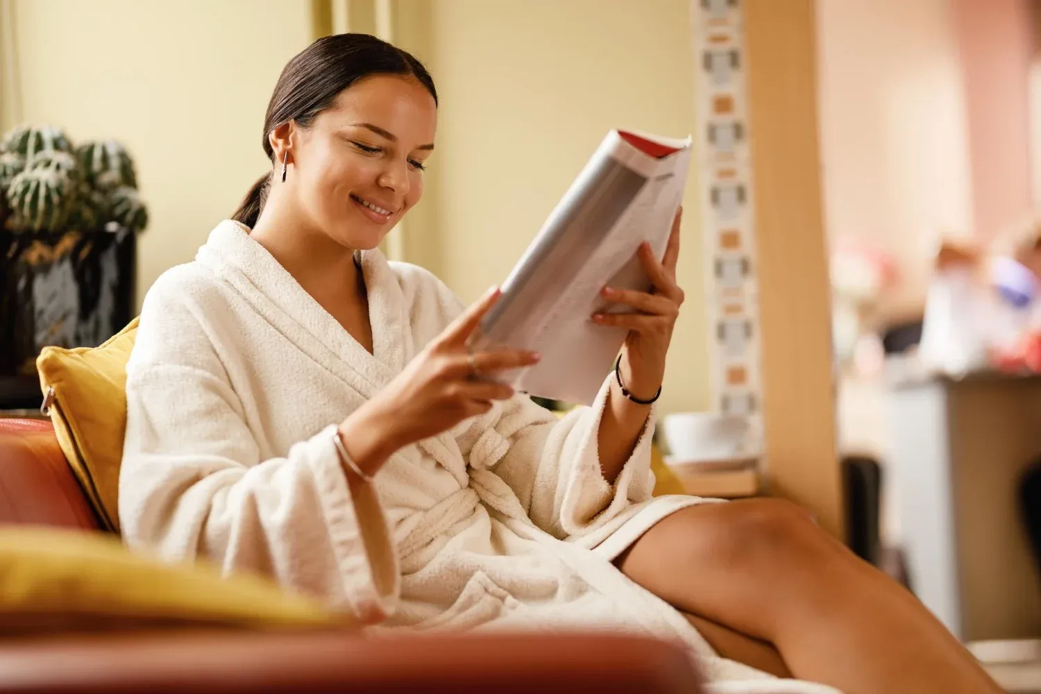 Mujer con bata leyendo revista en hotel, Tequendama: Corporativa relajación.Jacuzzi interior con vista al lago y un pino, ideal para Tequendama: Corporativa.