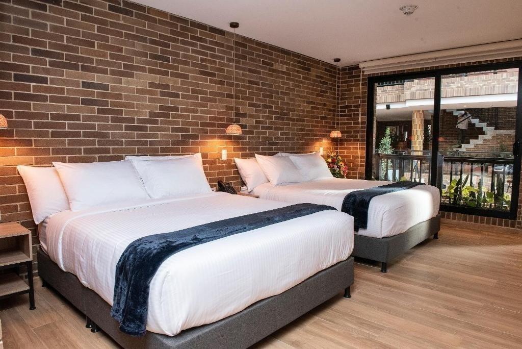 Two beds at Casa Rosé Hotel | Boutique Hotel in El Carmen de Viboral, featuring brick walls.