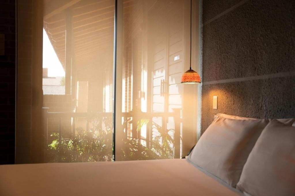 Cozy bedroom with hanging lamp and view of lush greenery at Casa Rosé Hotel | Boutique Hotel El Carmen de Viboral.
