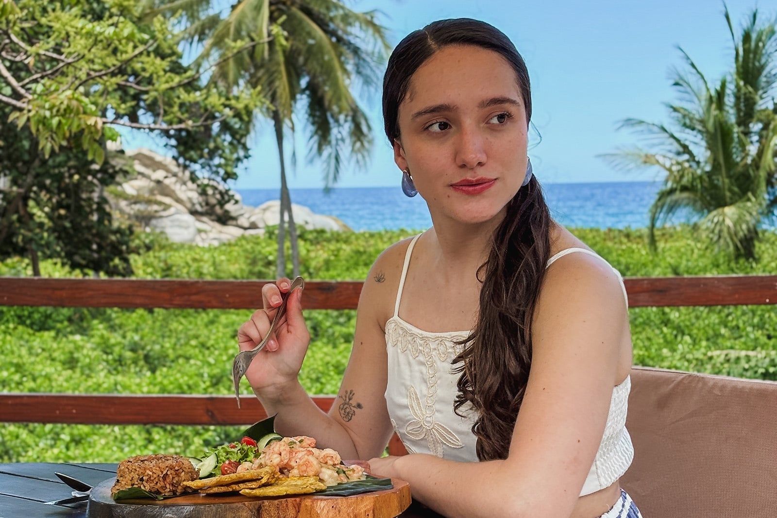 Mujer disfruta comida caribeña con vista al mar, ideal para Tequendama Corporativa.