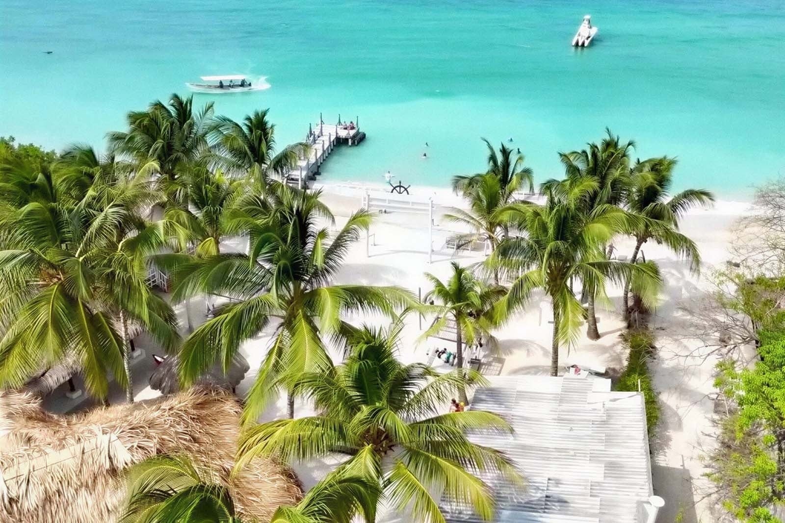 Playa tropical con palmeras y muelle del Marine Beach Club & Hotel en Cartagena.