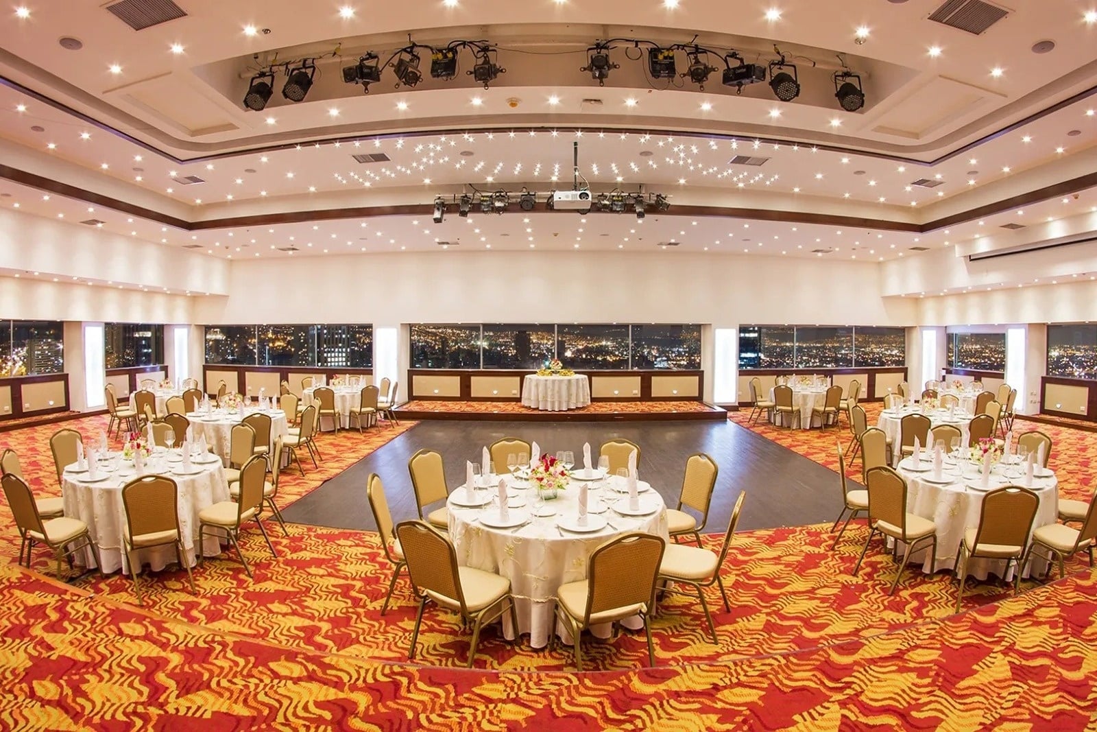Tequendama Corporate event hall: Banquet tables set with city night view.