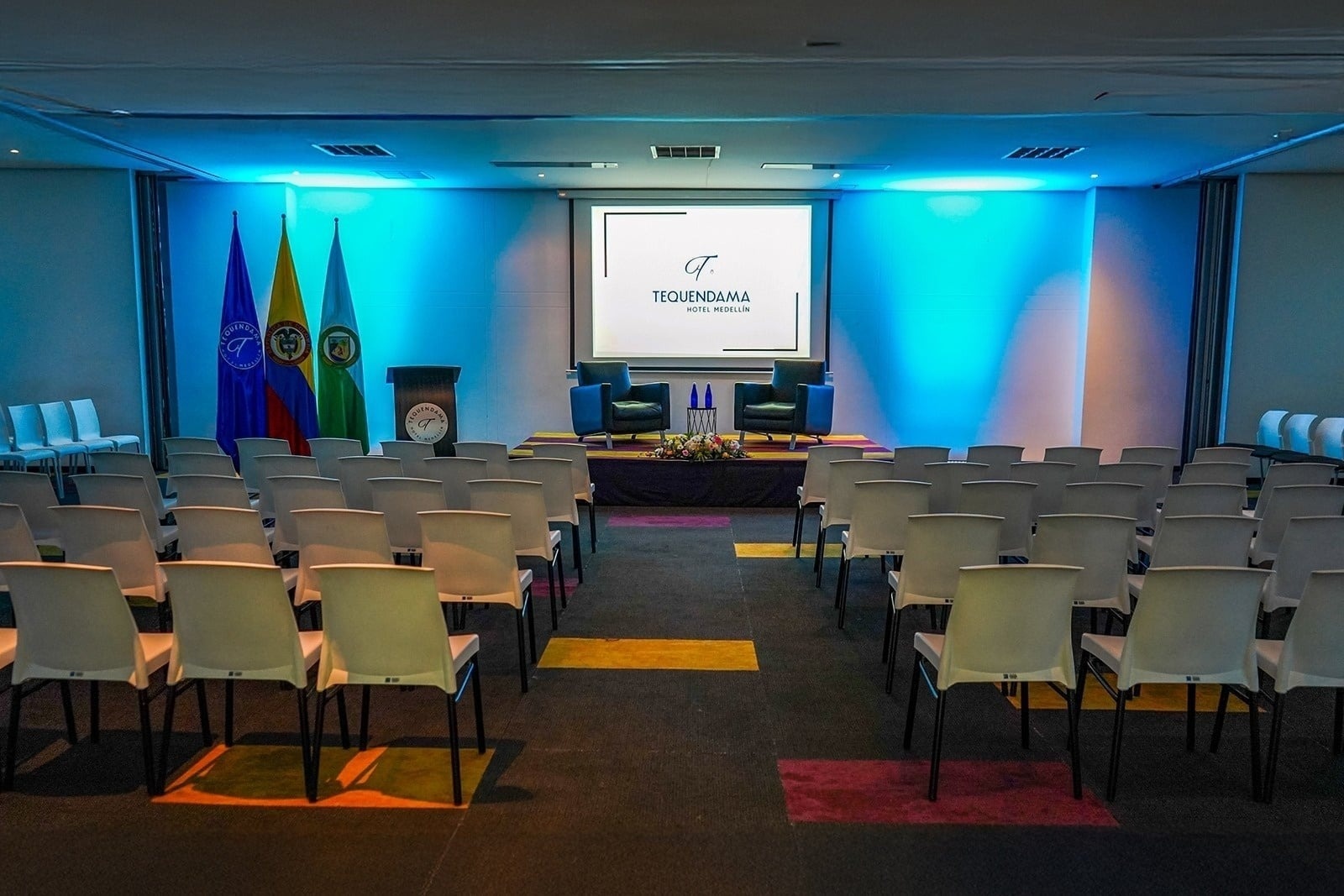Tequendama: Corporate room with white chairs and stage.