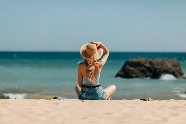 Mujer con sombrero en la playa, vistas al mar, ideal para Tequendama Hoteles.