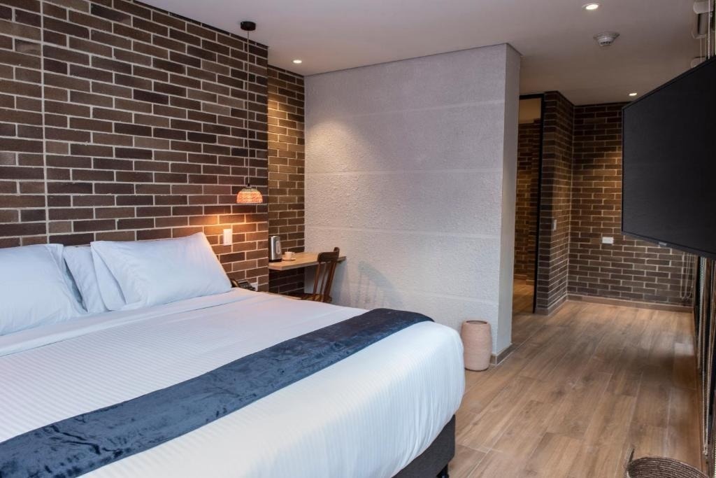 Modern hotel room at Casa Rosé Hotel, featuring brick walls and a comfortable bed.