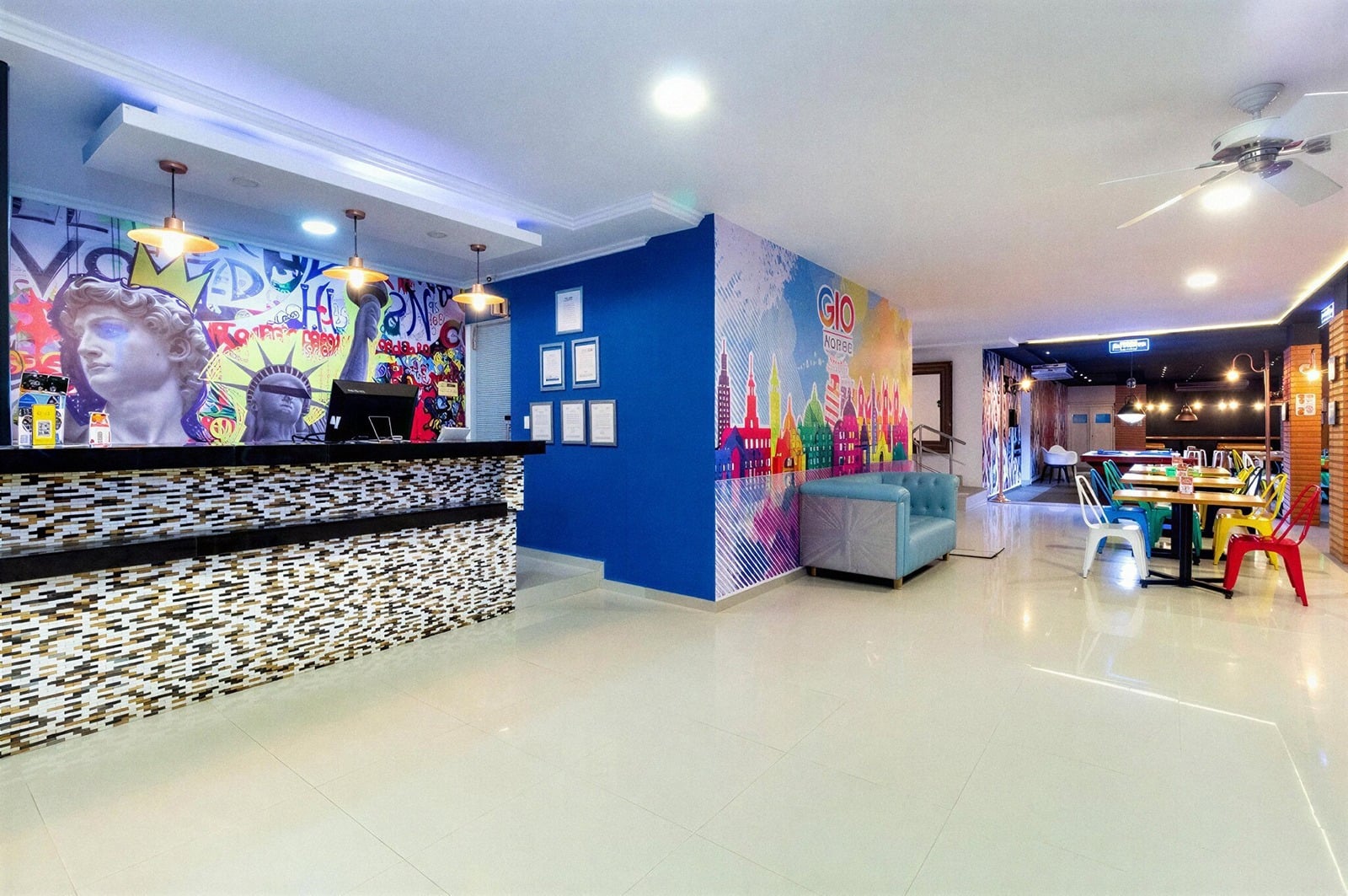 Recepción moderna de Gio Hotel Tama Cartagena con mural artístico y área de comedor.