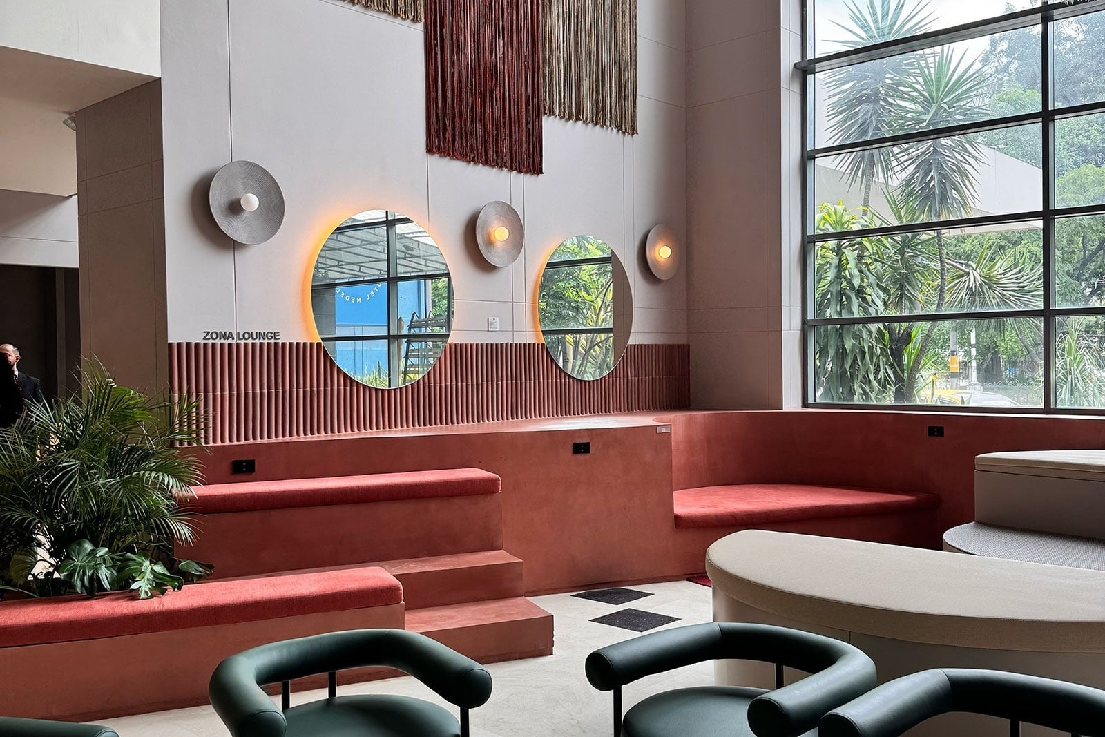 Tequendama Hotel Medellín: Modern lounge with circular mirrors and lush plants.