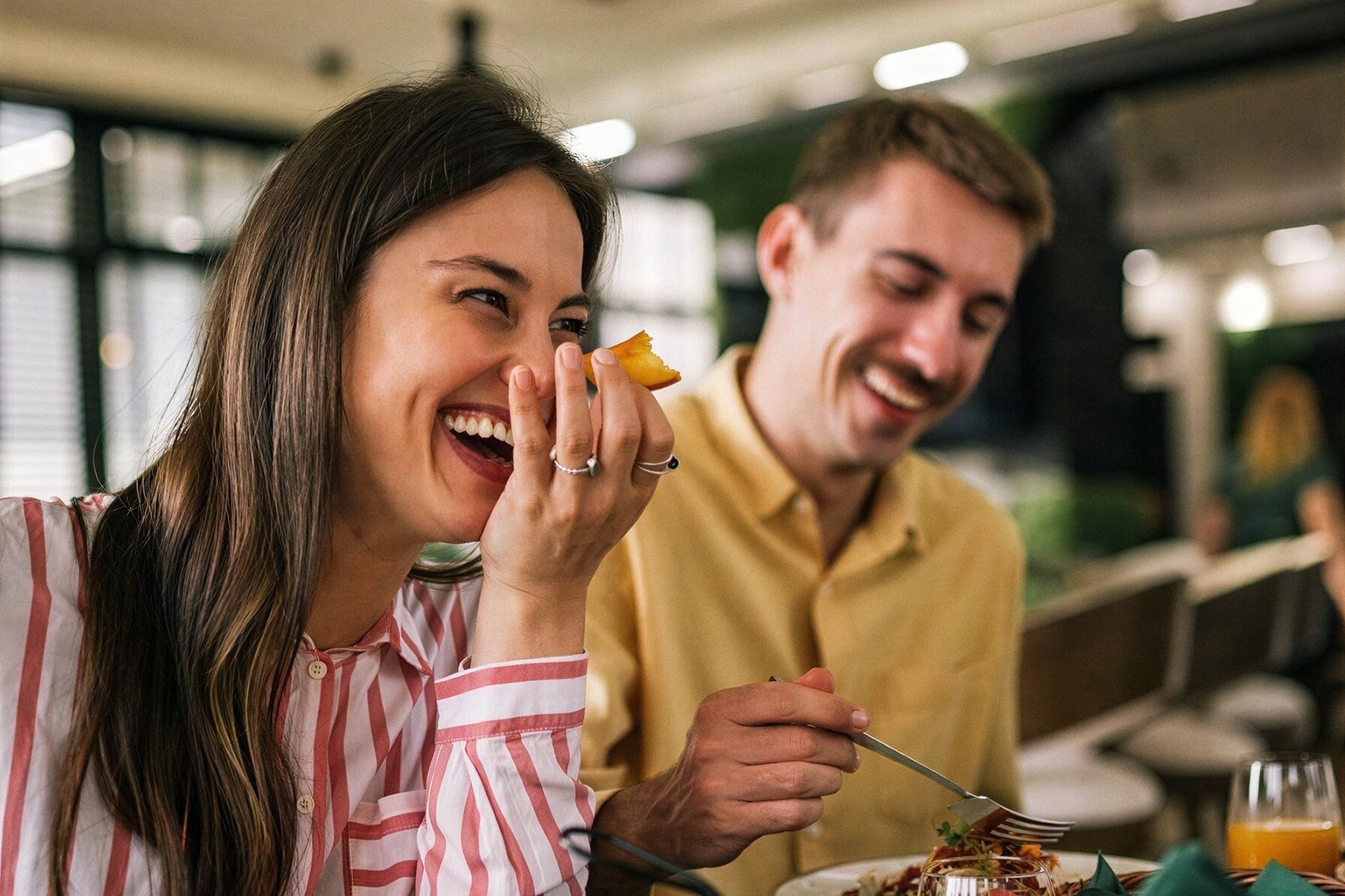 Pareja sonriendo en restaurante Tequendama: Corporativa, disfrutando comida.