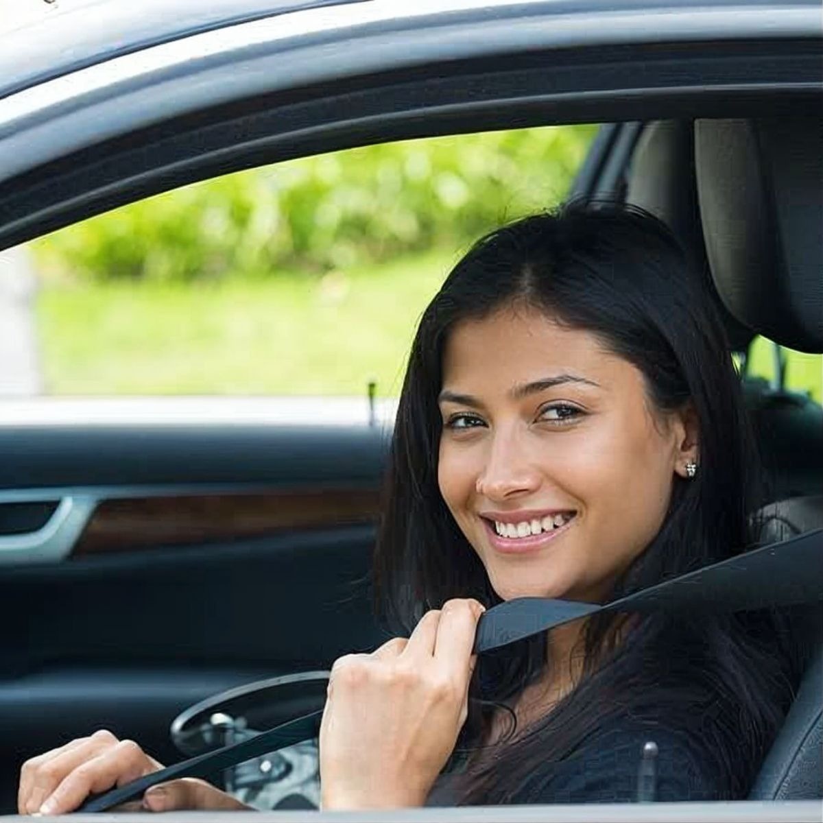 Tequendama: Corporativa. Mujer sonriendo abrochando cinturón de seguridad en auto.