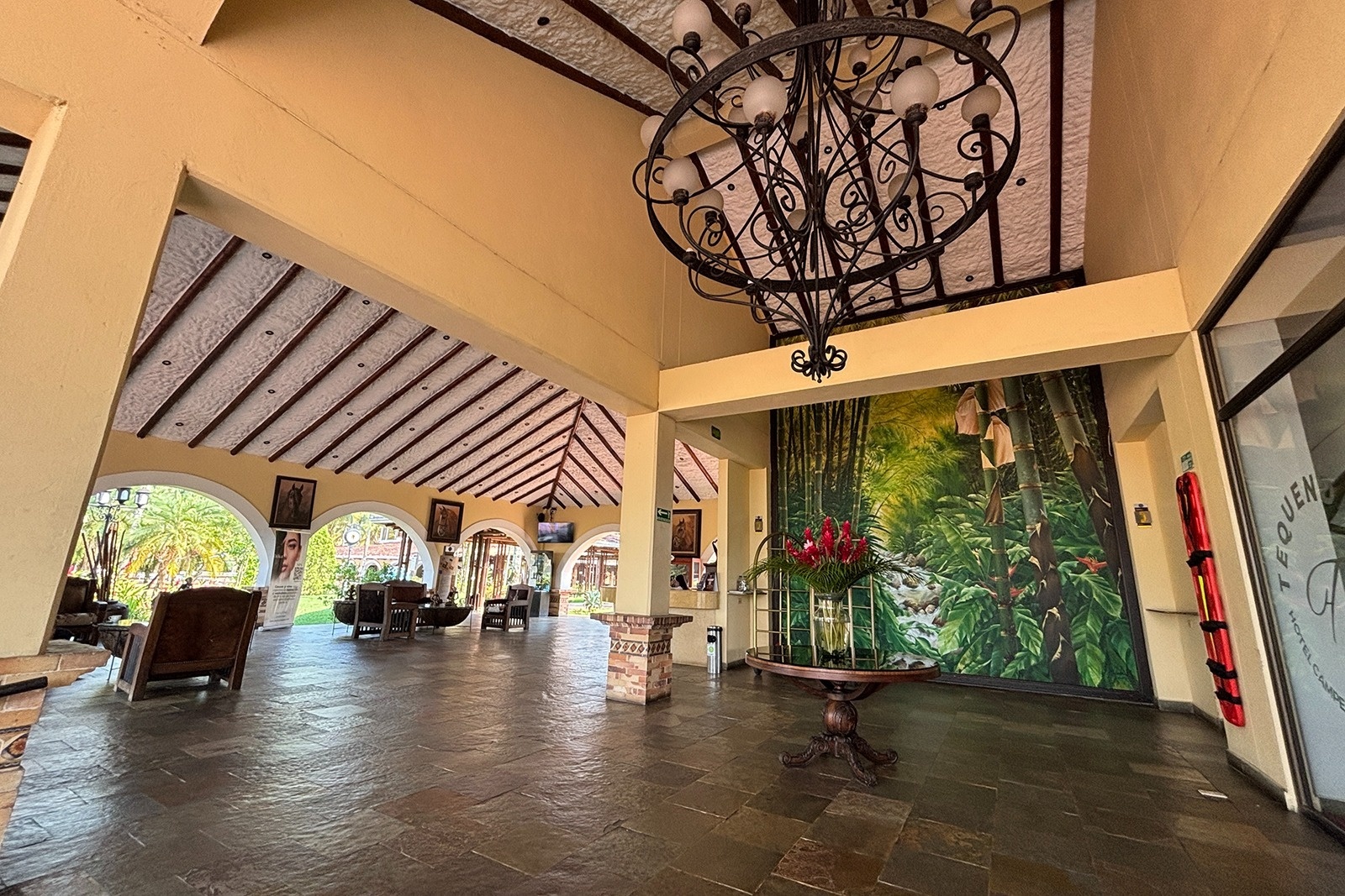 Lobby of Tequendama Hotel Campestre Villavicencio, featuring jungle mural, chandelier, and seating.