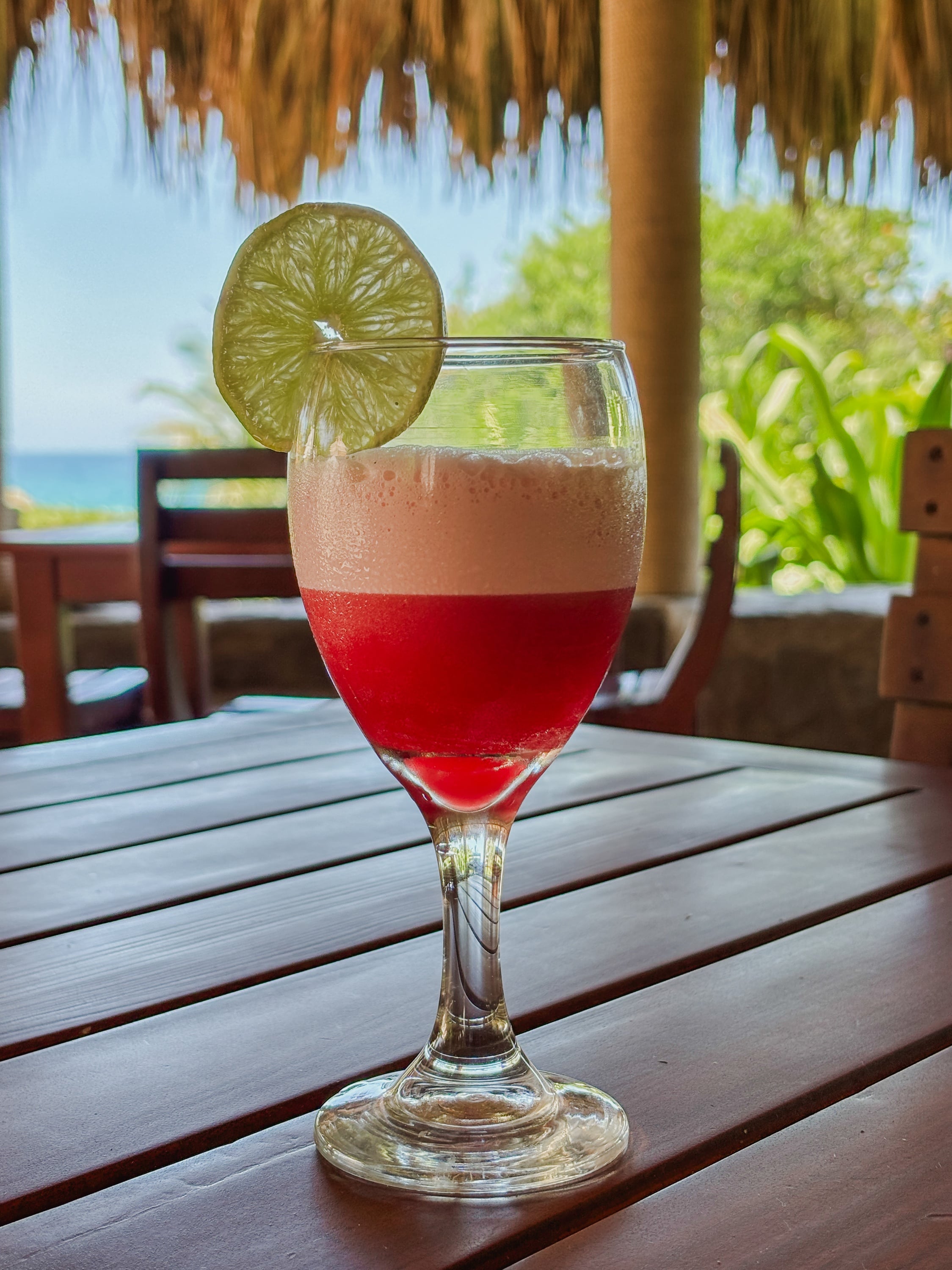 Cóctel tropical con rodaja de lima en mesa de madera, perfecto para Tequendama: Corporativa.