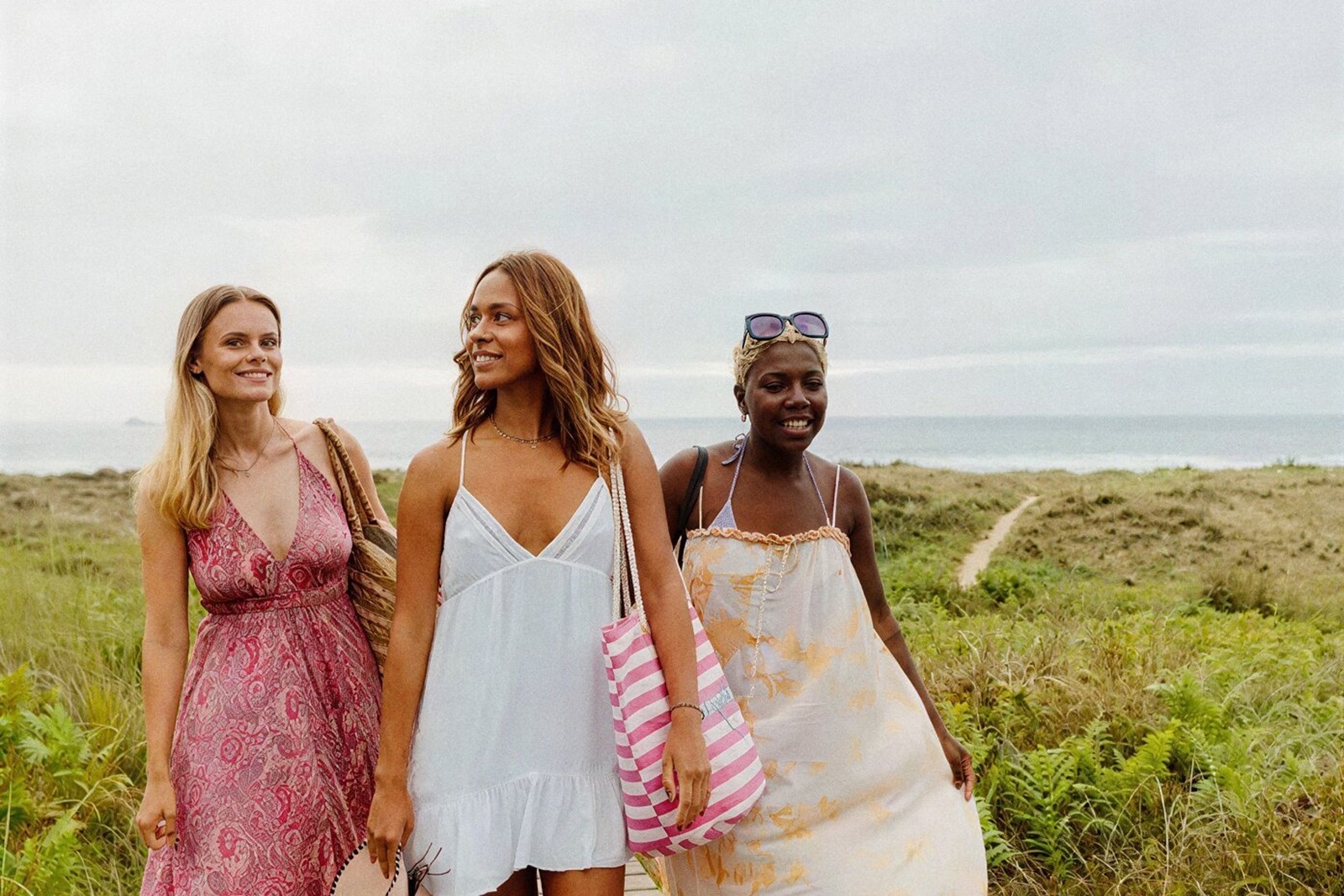 Tres mujeres sonrientes en Dresses con un fondo de playa, perfecto para Tequendama: Corporativa.