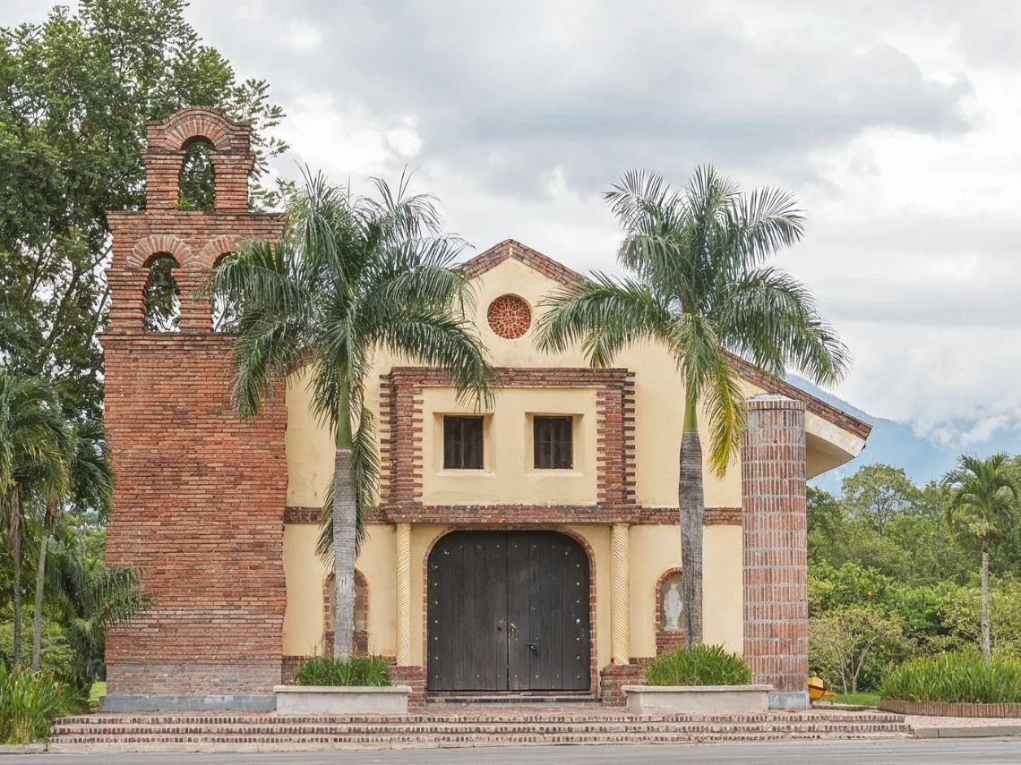Hotels in Villavicencio | Tequendama | Official Web: Church exterior with brick bell tower and palm trees.